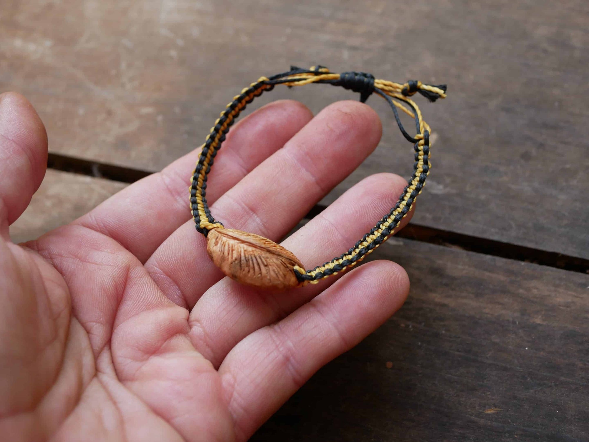 Makramee Armband mit einer Baumperle als Feder geschnitzt