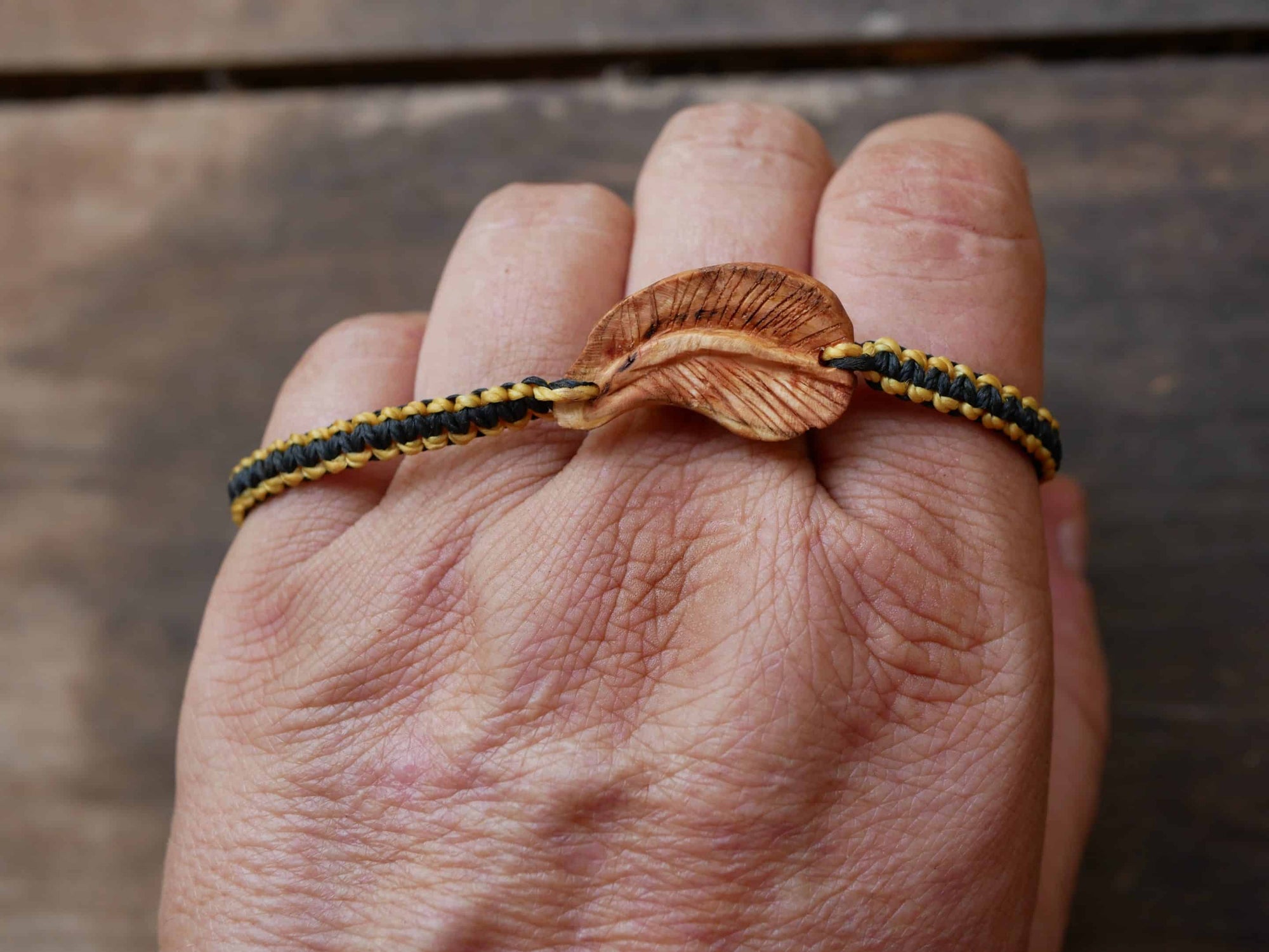 Makramee Armband mit einer Baumperle als Feder geschnitzt