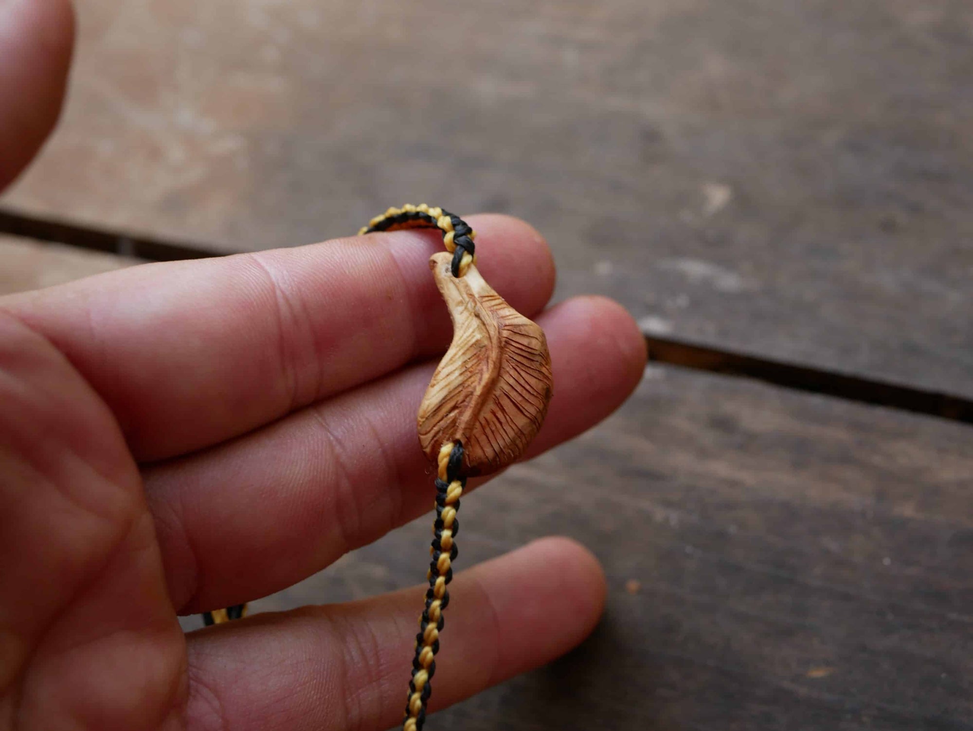 Makramee Armband mit einer Baumperle als Feder geschnitzt