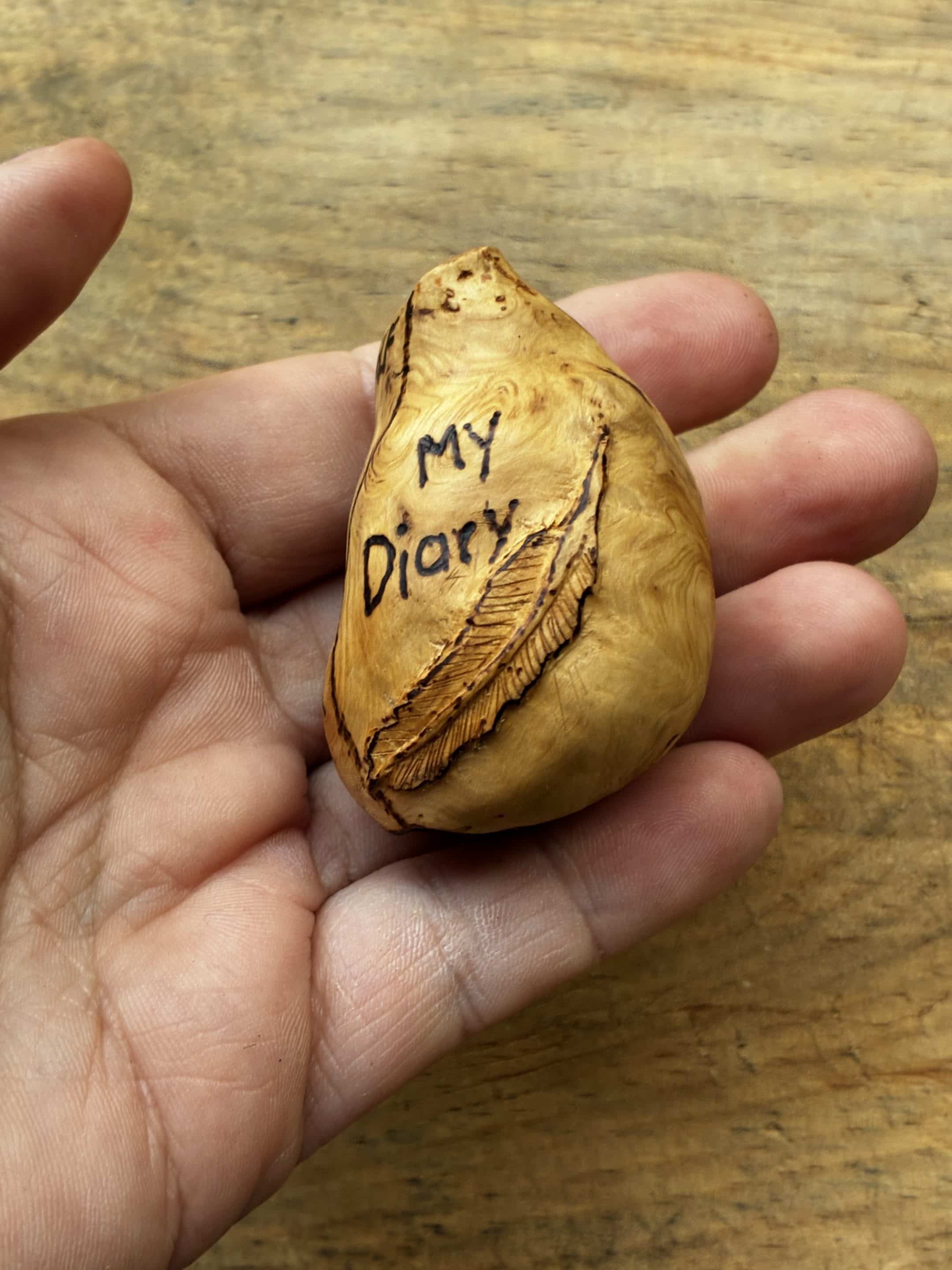 Buch aus Baumperle mit einer eingeschnitzten Feder