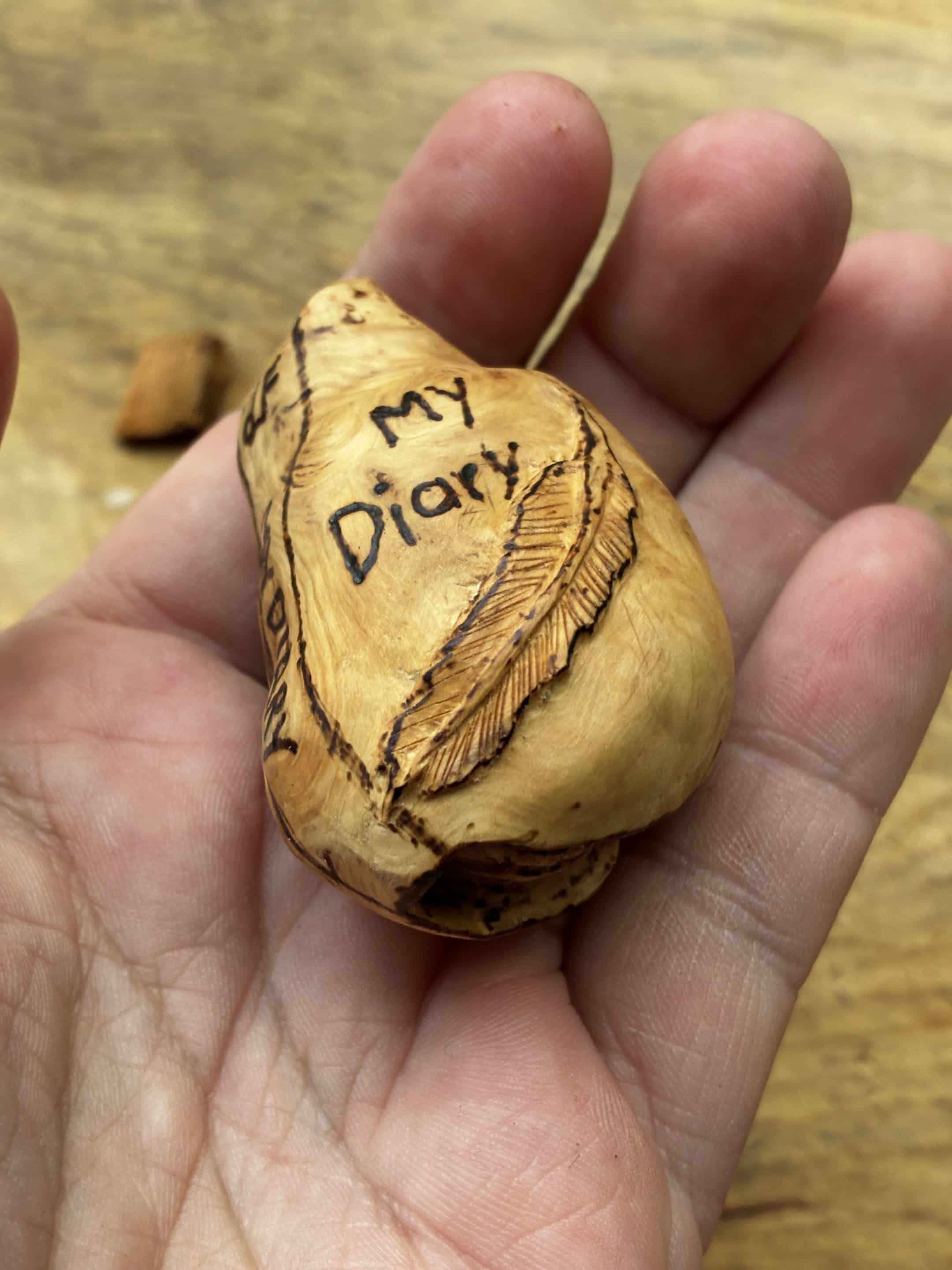 Buch aus Baumperle mit einer eingeschnitzten Feder