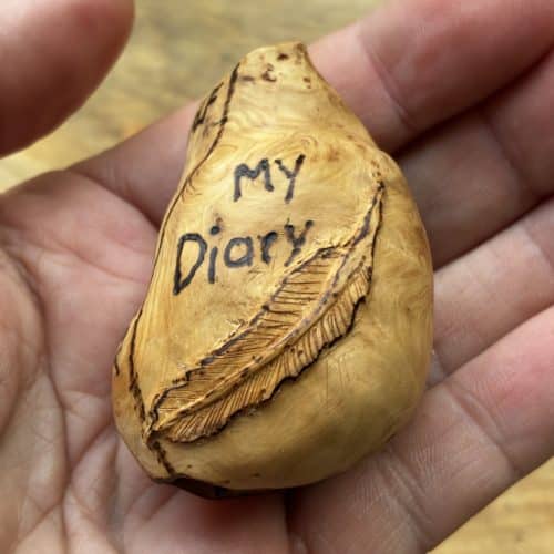 Buch aus Baumperle mit einer eingeschnitzten Feder