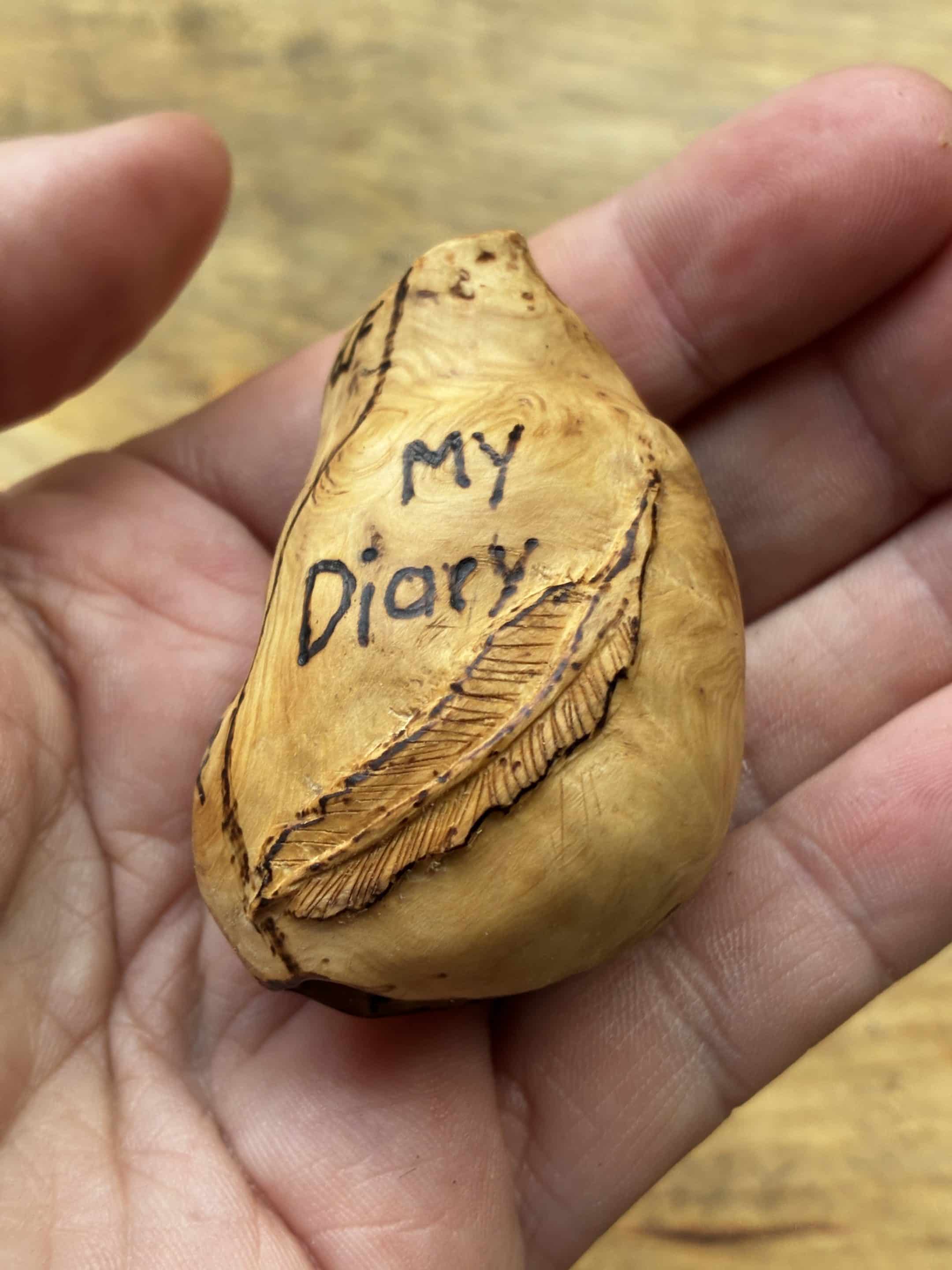 Buch aus Baumperle mit einer eingeschnitzten Feder