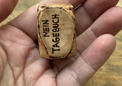 Buch aus Baumperle mit einer eingeschnitzten Feder