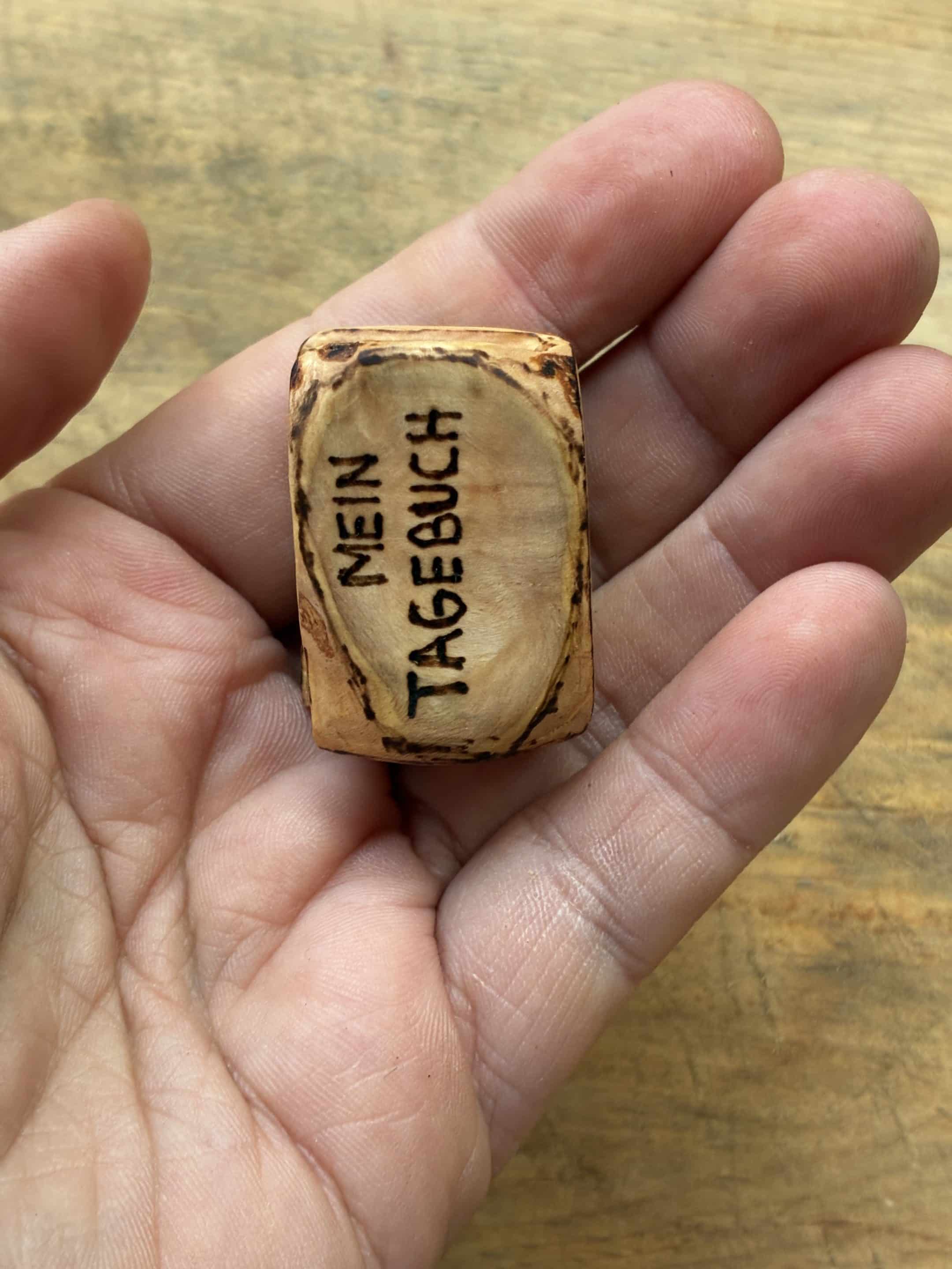 Buch aus Baumperle mit einer eingeschnitzten Feder