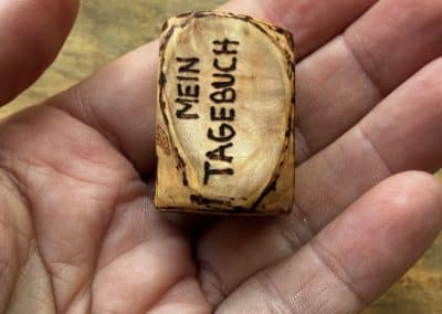 Buch aus Baumperle mit einer eingeschnitzten Feder