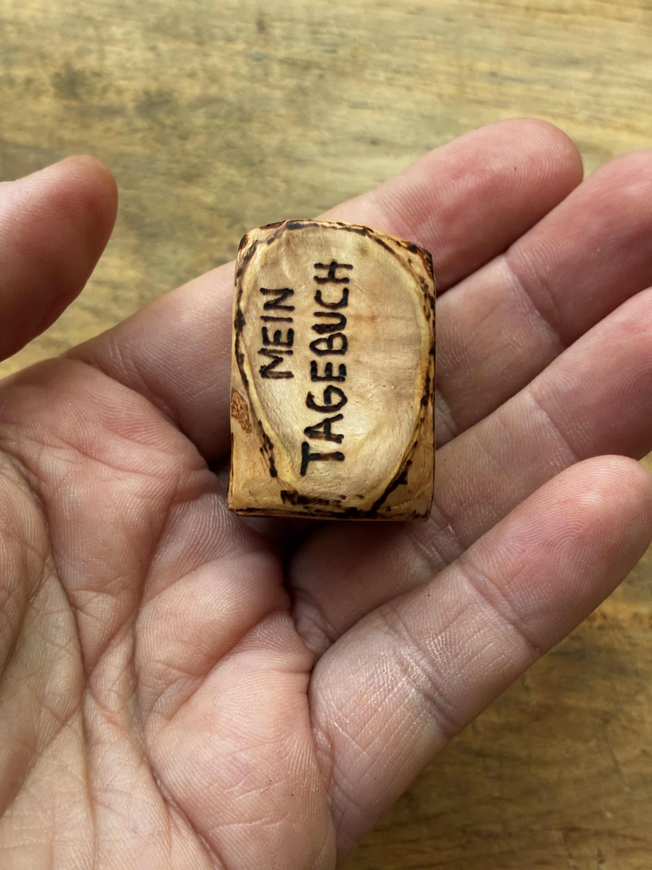 Buch aus Baumperle mit einer eingeschnitzten Feder