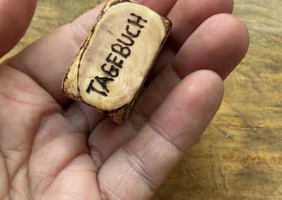 Buch aus Baumperle mit einer eingeschnitzten Feder