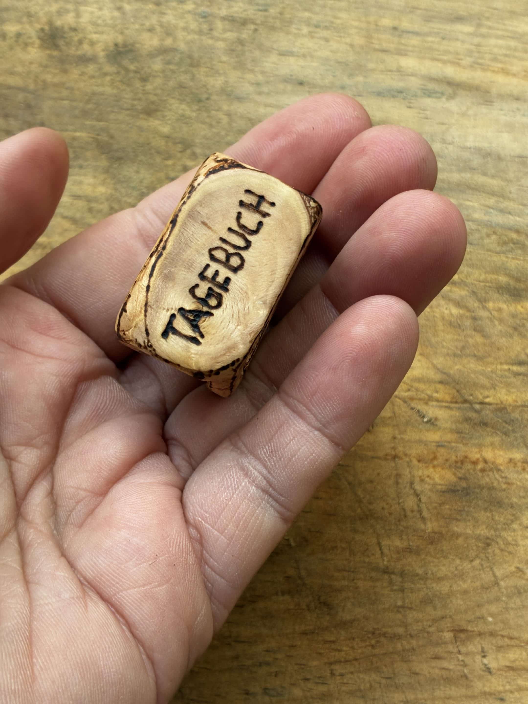 Buch aus Baumperle mit einer eingeschnitzten Feder
