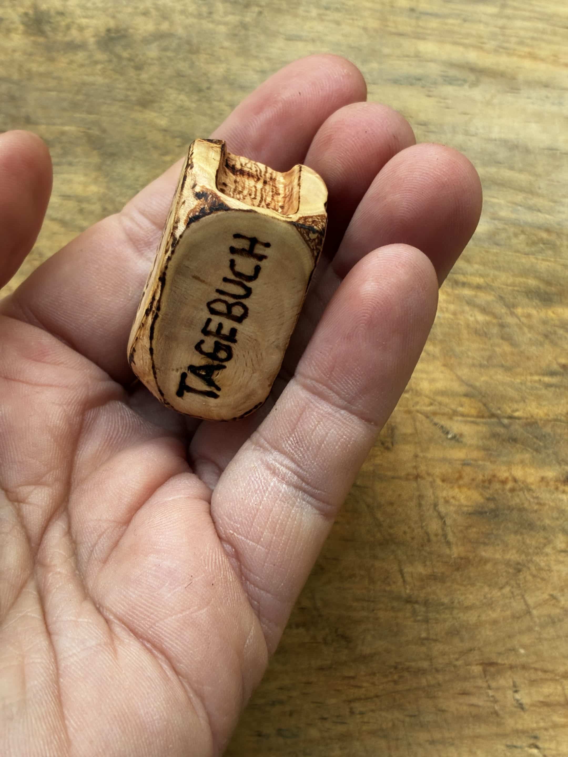 Buch aus Baumperle mit einer eingeschnitzten Feder