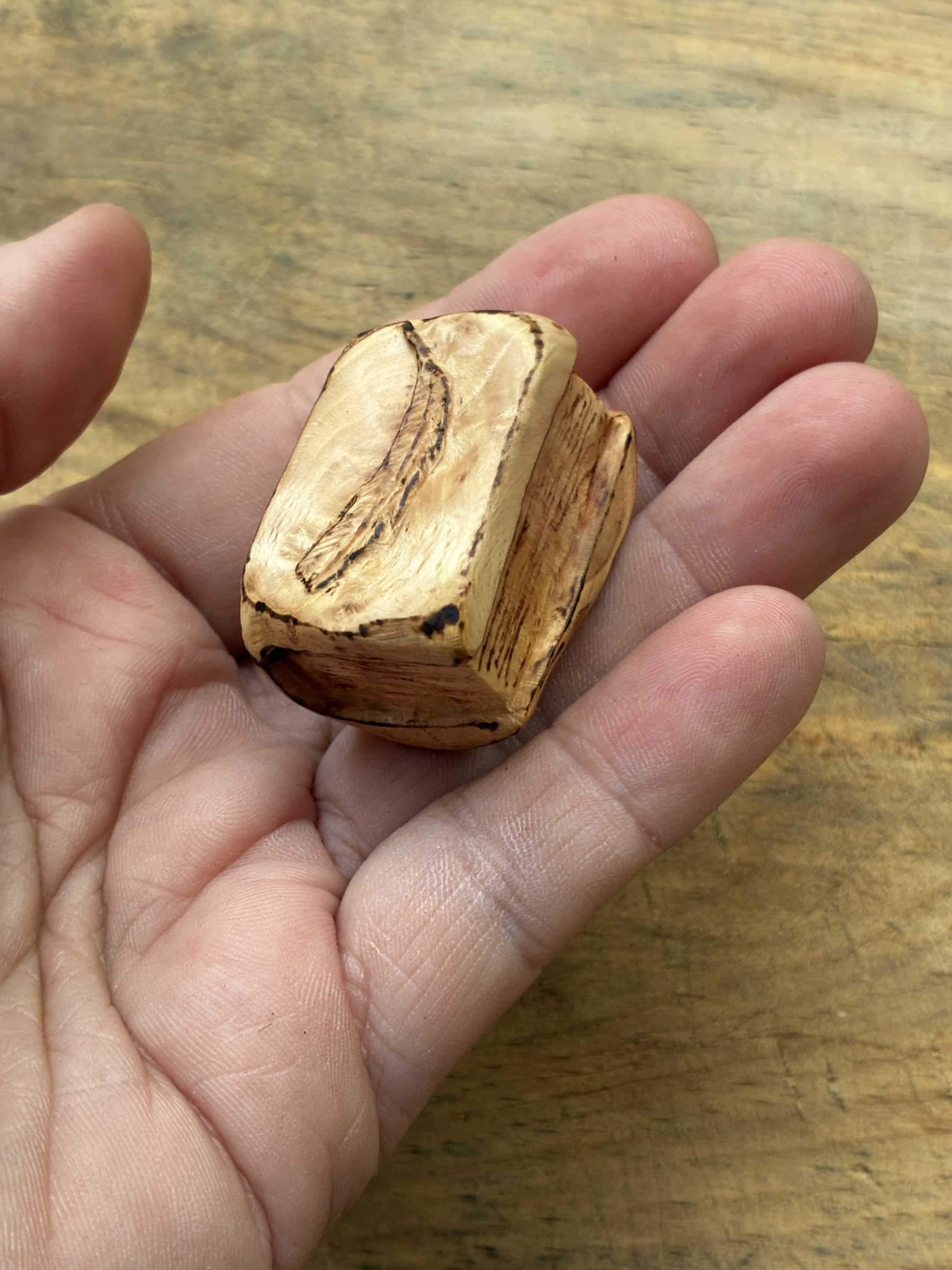 Buch aus Baumperle mit einer eingeschnitzten Feder