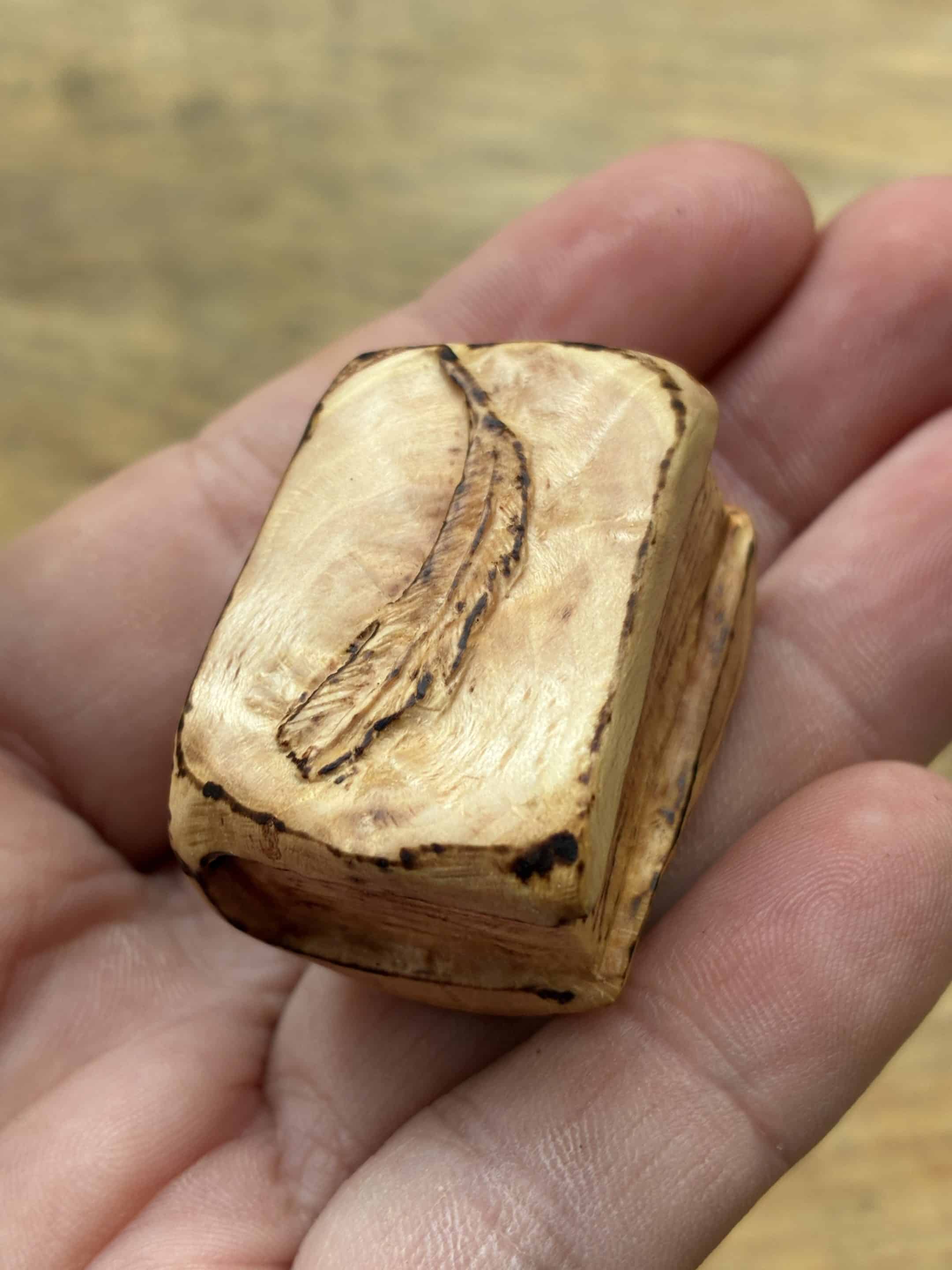 Buch aus Baumperle mit einer eingeschnitzten Feder